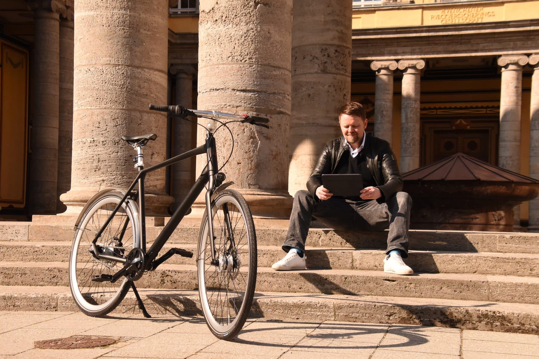 Mann sitzt mit einem Rad auf den Stufen am Königsplatz